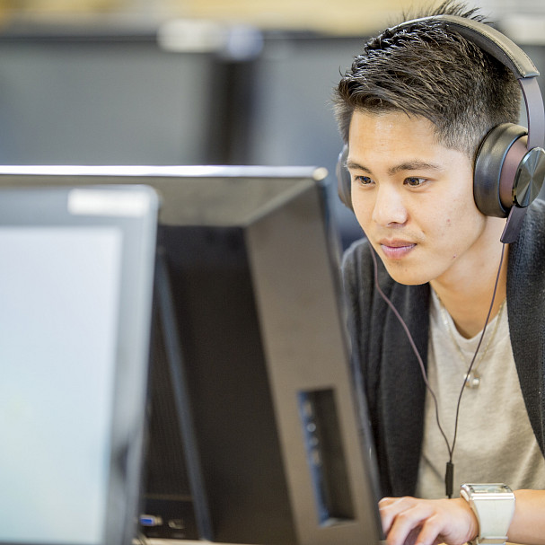 young man working in tech office with headphones on